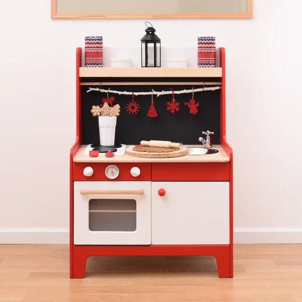 Designer toy kitchen ready for making cookies. Red and black kitchen for children with stove, oven and sink with cookies and raw dough