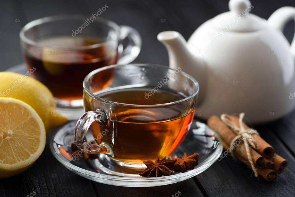 Spicy hot black tea in glass cup with lemon, cinnamon and star anise on