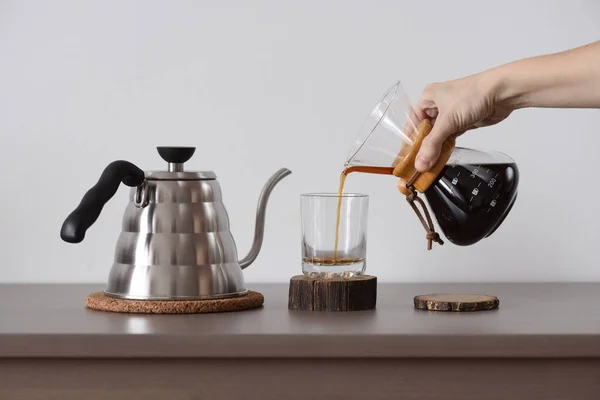 Brewing coffee in hand drip coffee maker. Woman hand pour coffee from drip coffee maker into glass