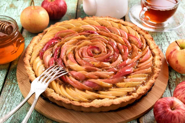 Homemade apple rose cake. Healthy delicious cake with tea, honey and fresh apples and silverware on rustic