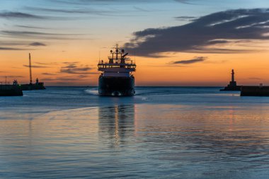Deniz kenarındaki sete, deniz feneri, gün doğumu ve gemi.