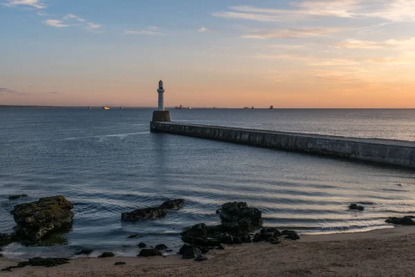 Sea wall, lighthouse, sunrise and ships. — Stock Photo, Image