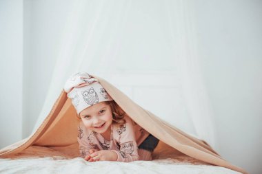 Adorable girl, looking out under a towel.