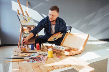 Sanatçı adam bitirme tarafından tasarlanmış eserini bir fırça elinde tutan