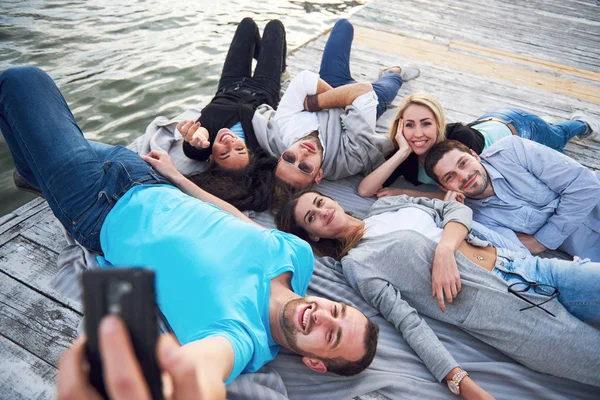 Groupe de beaux jeunes gens qui font Selfies couché sur la jetée, les meilleurs amis des filles et des garçons avec le concept de plaisir crée la vie émotionnelle des gens . — Photo