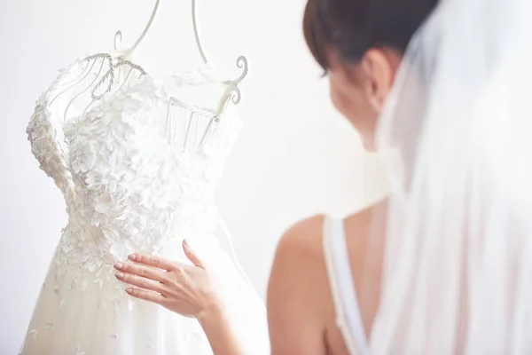 Elegant bride puts a wedding gown in her room.