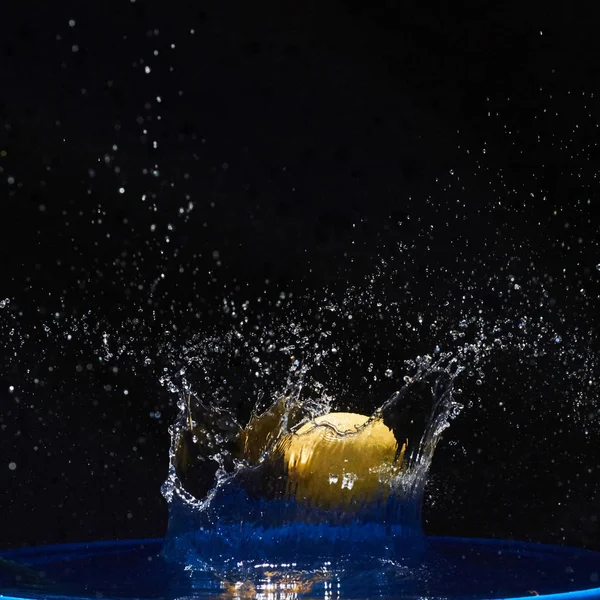 Żółta Cytryna Wpadająca Niebieskiej Wody Czarnym Tle — Zdjęcie stockowe