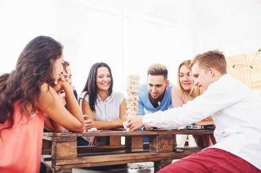 Bir grup yaratıcı arkadaş ahşap masada oturuyor. İnsanlar masa oyunu oynarken eğleniyor.