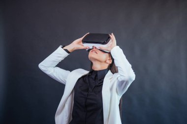 Happy woman on a black background in the studio gets the experience of using VR-glasses virtual reality headset clipart