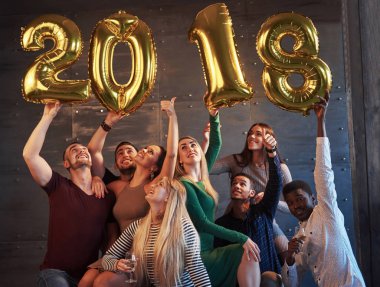 Bir grup neşeli genç, yeni bir 2018 yılının geldiğini belirten rakamlar tutuyor. Parti, yeni yılın kutlanmasına adanmıştır. Gençlik birlikteliği yaşam tarzı kavramları