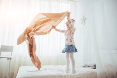 The little girl wants to wrap in a blanket in the bedroom light.