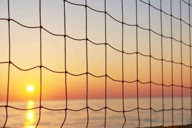 Denizin üzerinde güzel renkli bir gün batımı ve güneş parlıyor. Turuncu gökyüzü