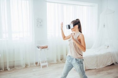 Kadın, parlak bir stüdyoda sanal gerçeklik kulaklığı kullanma deneyimi kazanır..