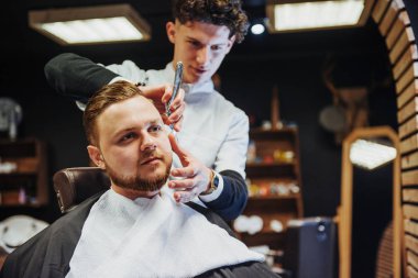 Man hairdresser doing haircut beard adult men in the men's hair salon.