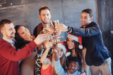 Yeni yıl geliyor! Partide Noel Baba şapkası takmış neşeli, çoklu etnik kökenli bir grup genç insan duygusal yaşam tarzı insanları konseptine poz veriyor..