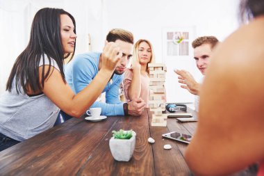 Bir grup yaratıcı arkadaş ahşap masada oturuyor. İnsanlar masa oyunu oynarken eğleniyor.