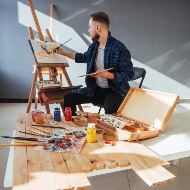 Sanatçı adam bitirme tarafından tasarlanmış eserini bir fırça elinde tutan