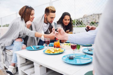 Mutlu genç arkadaşlar bir masada oturup dışarıda piknik yapıyorlardı..