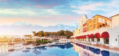 Tekirova Türkiye - 25 Nisan 2017: Yüzme havuzu ve lüks otelin plajı. Tip eğlence kompleksi. Güneşli bir günde arka planda karlı dağlar sisli olur. Amara Dolce Vita Luxury Oteli. Tatil köyü. Tekirova-Kemer. Türkiye