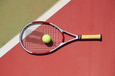 Tenis raketi ve yeni boyanmış tenis kortunda yeni bir tenis topu.