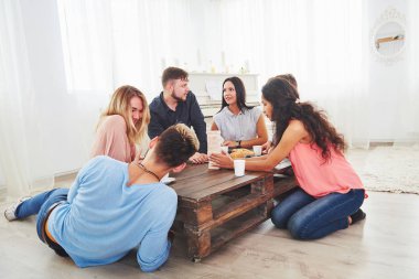 Bir grup yaratıcı arkadaş ahşap masada oturuyor. İnsanlar masa oyunu oynarken eğleniyor.