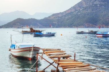 Kırık rıhtımın yakınındaki tekneler sakin, mavi bir deniz suyu koyuyor..