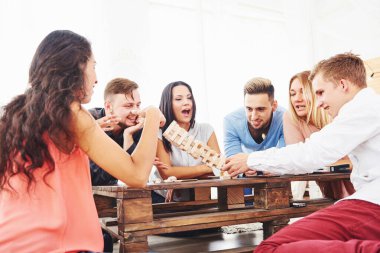 Bir grup yaratıcı arkadaş ahşap masada oturuyor. İnsanlar masa oyunu oynarken eğleniyor.