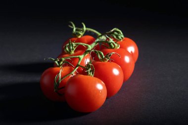 Siyah arkaplanda kırmızı organik domates dalı