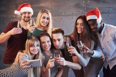Yeni yıl partisinde selfie çeken genç ve güzel gruplar, en iyi arkadaşlar kızlar ve erkekler birlikte eğleniyorlar, hayat tarzı insanları poz veriyorlar. Şapkalar ve şampanya kadehleri ellerinde..