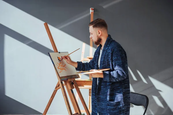artist painting a picture in a studio.