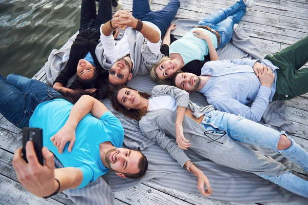 Groupe de beaux jeunes gens qui font Selfies couché sur la jetée, les meilleurs amis des filles et des garçons avec le concept de plaisir crée la vie émotionnelle des gens . — Photo