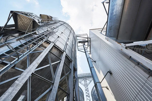 Agricultural Silos. Building Exterior. Storage and drying of grains, wheat, corn, soy, sunflower against the blue sky with white clouds.