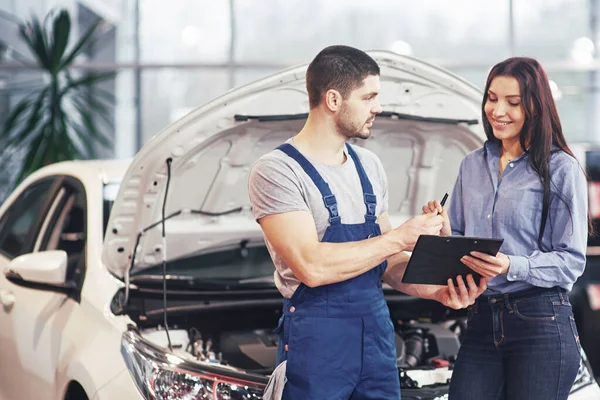 A man mechanic and woman customer discussing repairs done to her vehicle.