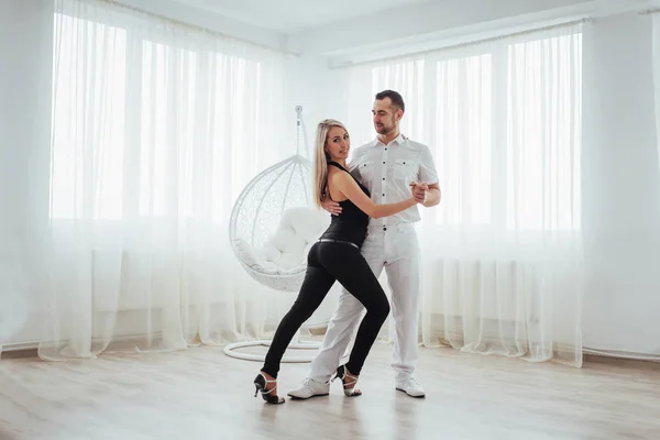 年轻夫妇跳舞拉丁音乐 Bachata 梅伦格 萨尔萨舞 白色房间的两个优雅姿势 — 图库照片