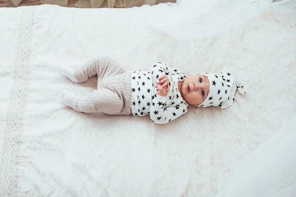 Novorozené Dítě Oblečené Bílém Obleku Černé Hvězdy Bílá Měkká Postel — Stock fotografie