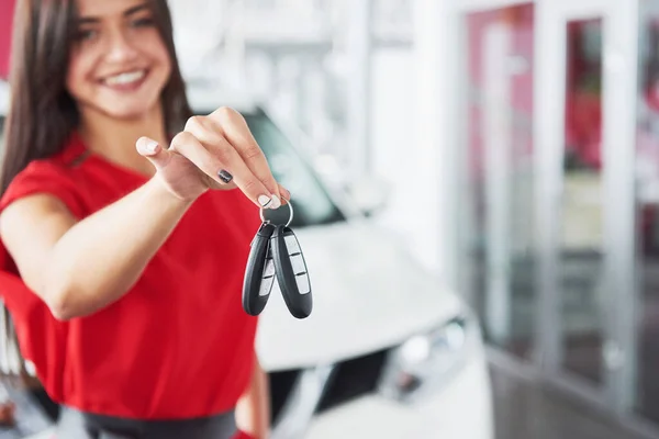 Smiling car salesman handing over your new car keys, dealership and sales concept. Happy girl the buyer.