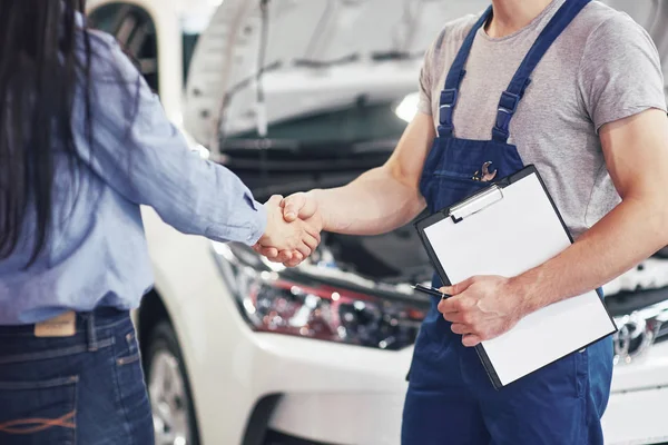 husband car mechanic and woman customer make an agreement on the repair of the car.