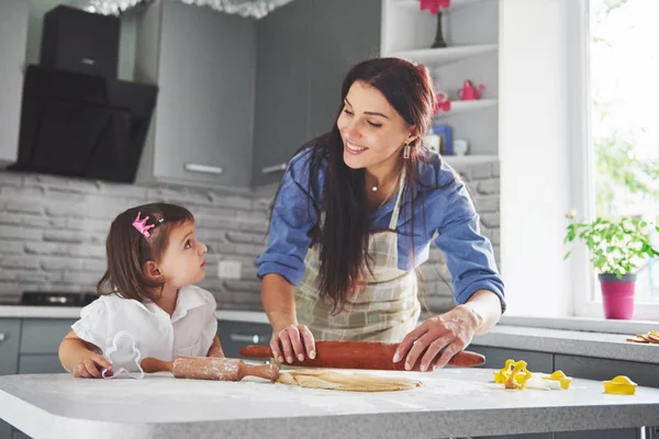 Happy family in the kitchen. Holiday food concept. Mother and daughter preparing the dough, bake cookies. Happy family in making cookies at home. Homemade food and little helper.