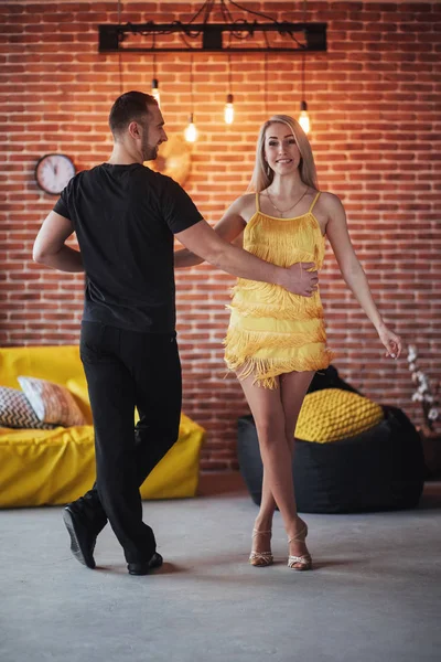Young couple dancing latin music: Bachata, merengue, salsa. Two elegance pose on cafe with brick walls.