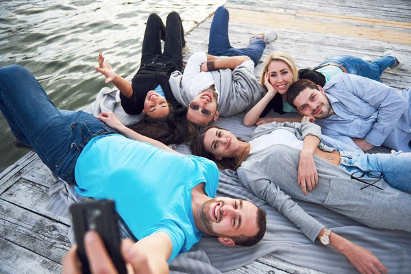 Portrait de jeunes amis heureux sur la jetée du lac. Tout en profitant de la journée et en faisant du selfie . — Photo