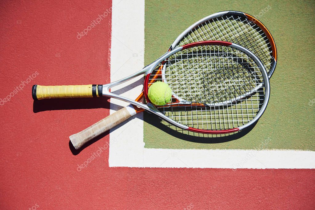 A tennis racket and new tennis ball on a freshly painted tennis court.