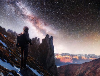 Samanyolu ile manzara, yıldızlı gece gökyüzü ve dağda duran bir fotoğrafçının silueti, tahıllı uzun pozlu fotoğraf.