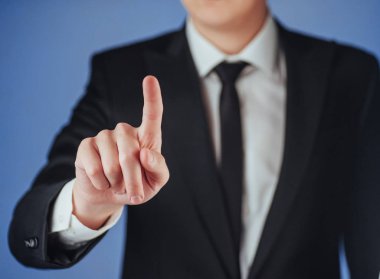 İşadamı, stüdyodaki siyah arka planda boş bir yeri işaret ediyor.