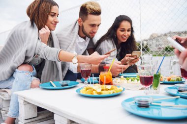 Mutlu genç arkadaşlar bir masada oturup dışarıda piknik yapıyorlardı..