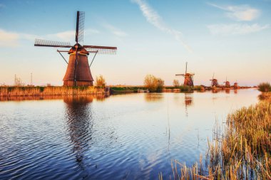 Renkli bahar günü ile geleneksel Hollanda Rotterdam kanalda yel değirmenleri. Ahşap iskele göl kıyısı yakınında. Holland. Hollanda.