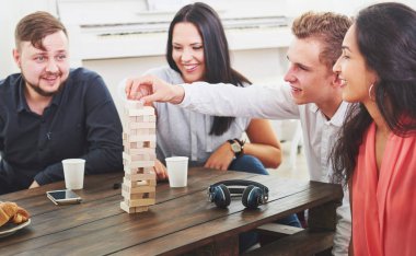 Bir grup yaratıcı arkadaş ahşap masada oturuyor. İnsanlar masa oyunu oynarken eğleniyor.