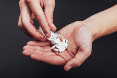 Bir adamın elinde cam kavanoz olan beyaz tabletler..