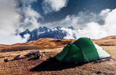 Fantastik yıldızlı gökyüzü. Çadır, karlı dağ zirvelerinin arka planında. Dağlardan Georgia 'daki Ushba Mheyer Dağı manzarası. Avrupa.