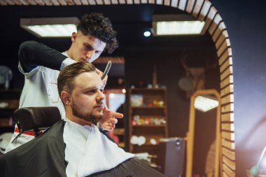 Man hairdresser doing haircut beard adult men in the men's hair salon.