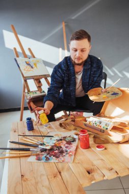 Sanatçı adam bitirme tarafından tasarlanmış eserini bir fırça elinde tutan